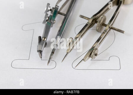 A companion for drawing circles on a white piece of paper. Drafting accessories for drawing technical drawings. Light background. Stock Photo
