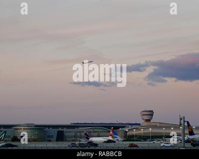 Airplane on takeoff above the Miami International Airport at dusk with Swiss Air jet in foreground, Miami, Florida, USA. Stock Photo