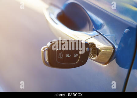 Modern car key inserted in lock close up on sunny day Stock Photo
