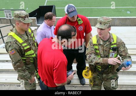 Army National Guard Sgt. Christopher Easterling of the Mississippi National Guard's 47th Civil Support Team explains the readings on radiation source detection equipment to Brandon Bell and Matt Bayley of the Hattiesburg Fire Department while Staff Sgt. John Dennis, Search Team Bravo noncommissioned officer-in-charge, looks on during a radiological threat and response exercise at the University of Mississippi's M.M. Roberts Stadium Jan. 17-18, 2017. The joint exercise also included other university, local, state, regional and federal agencies. (Mississippi National Guard Stock Photo