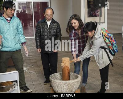 Members of the Kadena Teen Center and Okinawa City junior high school use a wooden mallet to pound rice to make mochi Jan. 21, 2017, at Koza Music City, Okinawa, Japan. The Let’s Learn English exchange builds relationships between Okinawan and American teenagers. Stock Photo