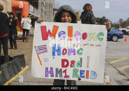 Son of PO1 Scott Reid shows off the sign him and his brother made for the return of their father at Camp Lejeune, N.C., Jan. 10, 2017. Reid was on a nine-month deployment with Special Purpose Marine Air-Ground Task Force Crisis Response-Africa; a rotation in place to protect U.S. personnel, property and interests in Europe and Africa. Reid is a Corpsman with 2nd Marine Logistics Group. Stock Photo