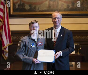 Illinois Governor Bruce Rauner presents Staff Sgt. Ethan Wheeler of Trenton, Illinois, assigned to the 126th Operations Support Squadron a congratulatory letter for being selected to receive the U.S. Air National Guard’s Staff Sergeant Henry “Red” Erwin Outstanding Enlisted Aircrew Member of the Year Award. During the time period covered for the award, Wheeler deployed to Southwest Asia where he completed 61 combat aerial refueling missions and encountered five in-flight emergencies involving coalition fighter aircraft and his own KC-135 Stratotanker.  While in theater, he also flew over 670 o Stock Photo