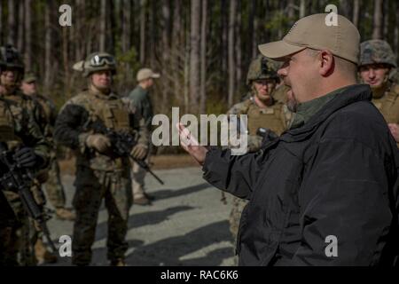Marines with 2nd Assault Amphibian Battalion gather to listen as John Galloway, a counter-Improvised Explosive Device instructor with the Marine Engineer School, gives them corrective feedback during a mounted CIED convoy operation at Camp Lejeune, N.C., Jan. 11, 2017. The training is designed to familiarize the Marines with procedures to better operate under the threat of IED’s while still maintaining tactical control of their situation and surroundings. Stock Photo