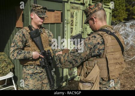 U.S. Marine Corps Lance Cpl. Yosef A. Charriez-Deleleon, left, Embarkation Specialist, Service Company, Combat Logistics Regiment (CLR) 2, 2nd Marine Logistics Group (MLG), and Lance Cpl. Nicolas J. Chairez, Chemical Biological Radiological Nuclear Specialist, Headquarters Company, CLR-2, 2nd MLG, perform the proper duty change over procedures during a command post exercise (CPX) at Landing Zone Canary on Camp Lejeune, N.C., Jan. 18, 2016. CLR-2 conducted the CPX in preparation for an upcoming deployment. Stock Photo