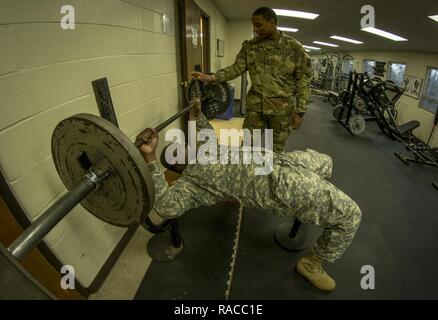 U.S. Army Reserve Sgt. Christopher Duncan, of Columbus, Ga., spots Pvt. 1st Class Dunta Smith, a logistical supply specialist from Atlanta, as they exercise during their lunch break in the gym in the 335th Signal Command (Theater) headquarters building in East Point, Ga., Jan. 21, 2017. Both soldiers are with Charlie Company, 324th Expeditionary Signal Battalion. Stock Photo