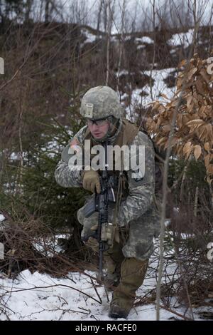 A Soldier assigned to Alpha Company, 3rd Battalion, 172nd Infantry Regiment, 86th Infantry Brigade Combat Team (Mountain), Vermont National Guard, moves toward an objective, at Camp Ethan Allen Training Site, Jericho, Vt., January 23, 2017. The Soldiers performed squad ambush exercises as part of their winter annual training. Stock Photo