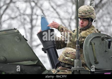 A U.S. Soldier, assigned to Headquarter and Headquarters Troop, 1st Squadron, 2d Cavalry Regiment, loads a 120mm mortar round into a Stryker mounted 120mm RMS6L mortar at the 7th Army Training Command’s Grafenwoehr Training Area, Germany, Jan. 24, 2017.The Squadron trains and prepares to support Atlantic Resolve later this year.  Atlantic Resolve improves interoperability, strengthens relationships and trust among allied armies, contributes to regional stability, and demonstrates U.S. commitment to NATO. Stock Photo