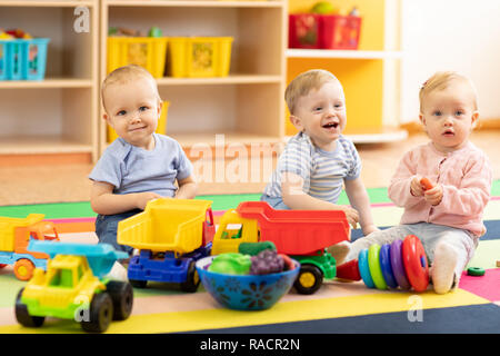 Group of babies is playing on floor in nursery or creche. Children in the day care center. Fun in the children's playroom Stock Photo