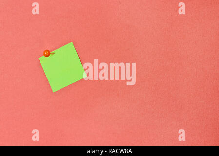 Blank green note pad paper over coral color background with free space for text. Image shot from above. Stock Photo