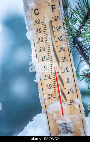 Thermometer on snow shows low temperatures - zero. Low temperatures in  degrees Celsius and fahrenheit. Cold winter weather - zero celsius thirty  two farenheit