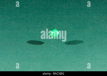 One green dice falling on a green table Stock Photo