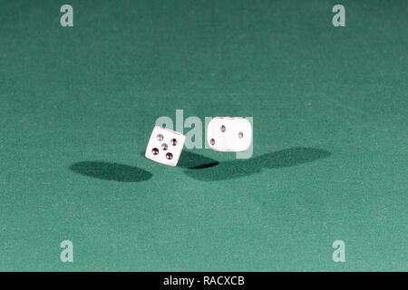 Two white dices falling on a green table Stock Photo