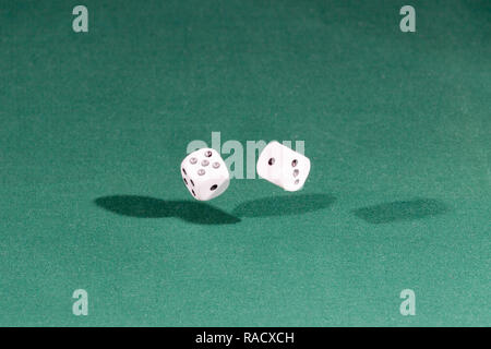 Two white dices falling on a green table Stock Photo