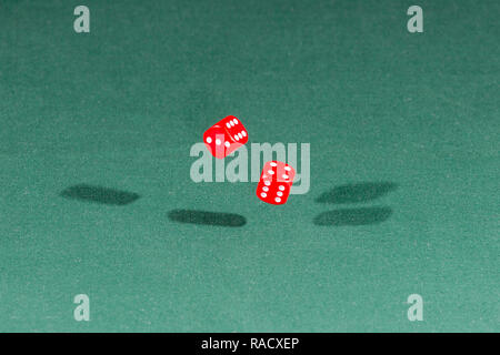 Two red dices falling on a green table Stock Photo