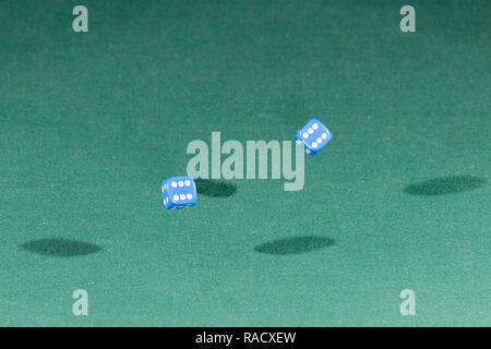 Two blue dices falling on a green table Stock Photo