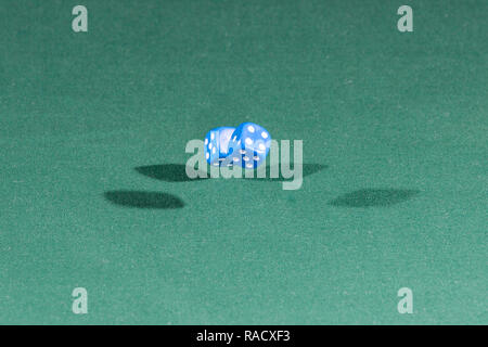 Two blue dices falling on a green table Stock Photo