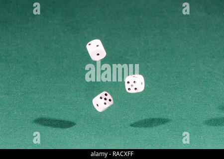 Three white dices falling on a green table Stock Photo