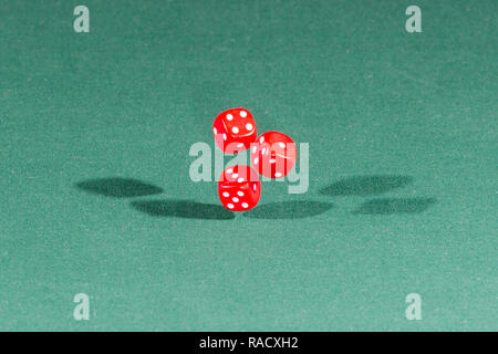 Three red dices falling on a green table Stock Photo