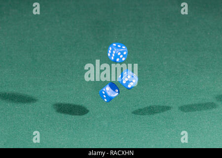 Three blue dices falling on a green table Stock Photo