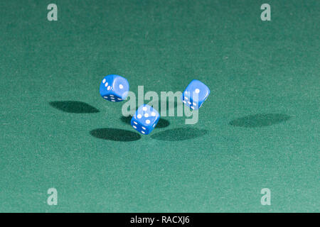 Three red dices falling on a green table Stock Photo