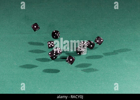 Ten black dices falling on a green table Stock Photo