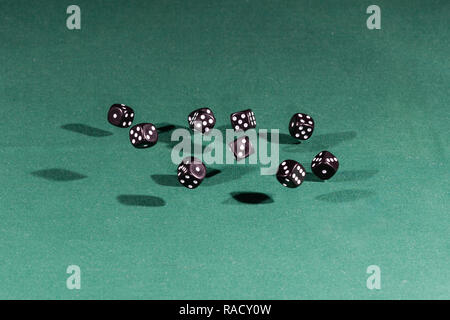 Ten black dices falling on a green table Stock Photo