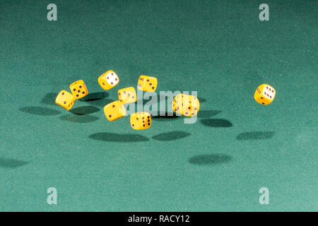 Ten yellow dices falling on a green table Stock Photo