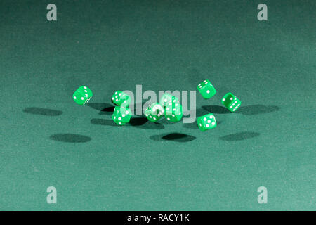 Ten green dices falling on a green table Stock Photo