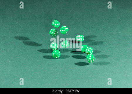 Ten green dices falling on a green table Stock Photo