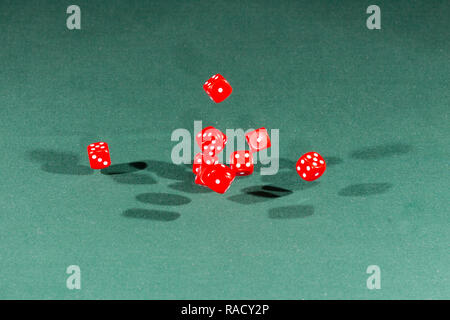 Ten red dices falling on a green table Stock Photo