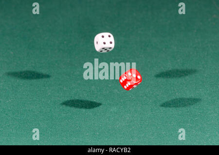Two red and white dices falling on a green table Stock Photo