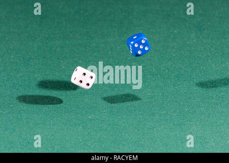 Two white and blue dices falling on a green table Stock Photo