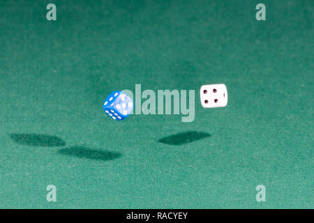 Two white and blue dices falling on a green table Stock Photo