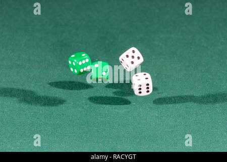 Four white and green dices falling on a green table Stock Photo