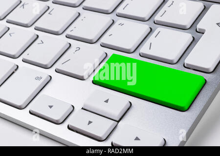 Close up view of a Computer notebook keyboard with one green button on office white table, technology background, empty space for text Stock Photo