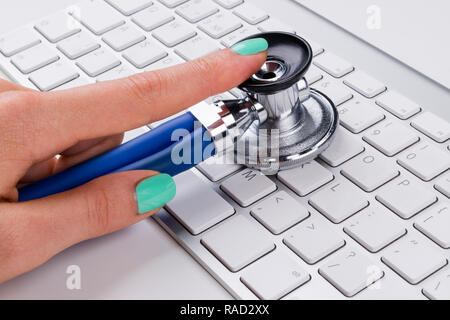 technician female (woman) hand using stethoscope for examines computer keyboard, computer service concept, computer and internet maintenance, checking Stock Photo