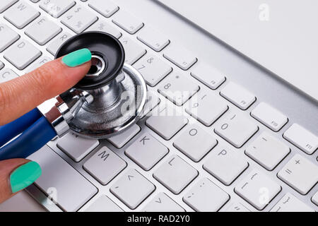 technician female (woman) hand using stethoscope for examines computer keyboard, computer service concept, computer and internet maintenance, checking Stock Photo