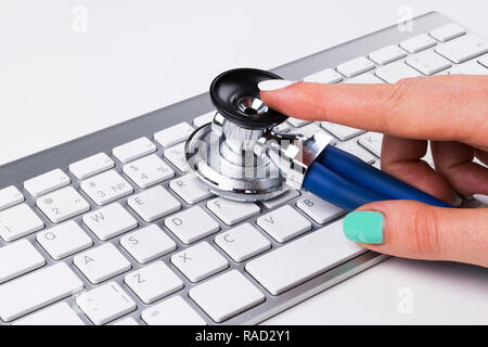 technician female (woman) hand using stethoscope for examines computer keyboard, computer service concept, computer and internet maintenance, checking Stock Photo