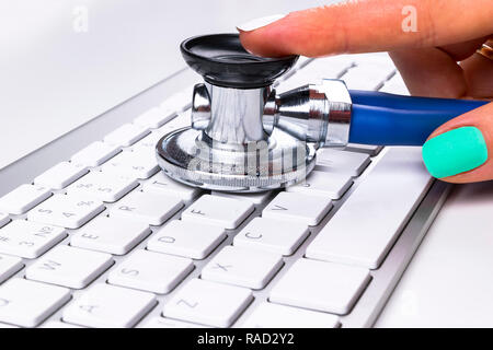 technician female (woman) hand using stethoscope for examines computer keyboard, computer service concept, computer and internet maintenance, checking Stock Photo