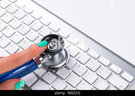 technician female (woman) hand using stethoscope for examines computer keyboard, computer service concept, computer and internet maintenance, checking Stock Photo