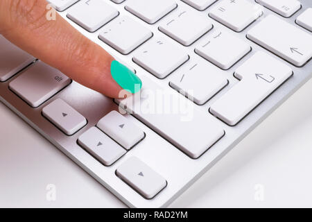 Close up view of a Finger Pushing Button on Aluminum Keyboard. Finger Pressing a Slim Aluminum Keyboard Button.Modern Laptop Keyboard Stock Photo
