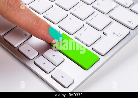 Close up view of a Finger Pushing on a green Button of computer Keyboard. Finger Pressing a Slim Aluminium Keyboard Button.Modern Laptop Keyboard. Emp Stock Photo