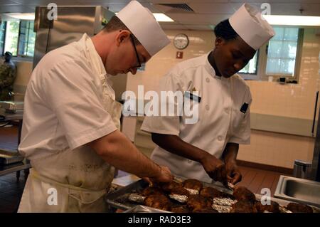 Spc. James Newberry (left), assigned to HHC, 325th Bde. Support Bn., 3rd BCT, 25th ID, and Sgt. Dominique Martin, assigned to Co. F, 3-7th Field Artillery Regt., 25th Div. Artillery, 25th ID, prepare Jamaican jerked chicken at the Bronco Café, on Schofield Barracks, Hawaii, on Jan. 19, 2017. Newberry and Martin participated in Black Team during the 3rd BCT Top Chef Competition. Stock Photo