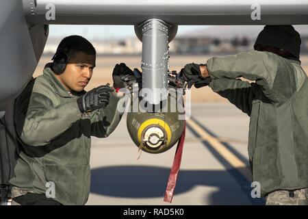 Airman First Class Carlos Quintanilla, left, and Staff Sgt. Tayrell Washington, 74th Aircraft Maintenance Unit weapons load team members, secure a Mark 82 general purpose bomb to the bottom of an A-10C Thunderbolt II during Green Flag-West 17-03, Jan. 24, 2017, at Nellis Air Force Base, Nev. Weapons Airmen enabled joint force training during the two-week exercise by loading weapons, inspecting jets and maintaining munitions systems. Some of the live munitions included the Mark 82 and 84 general purpose bombs, high-explosive incendiary 30mm rounds and the 500 pound GBU-12 Paveway II laser-guide Stock Photo