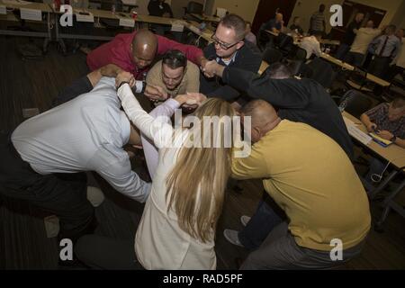 Senior leaders from across Marine Forces Reserve use teamwork to work on untangling themselves from a human knot while participating in an exercise during the Senior Leadership Workshop at Marine Corps Support Facility New Orleans, Feb. 23-26, 2017. The Marines and Sailors participated in multiple exercises and discussions that address differences in leadership styles, perspectives, experiences, backgrounds and more. The workshop aims to emphasize the importance of open communication and equal opportunity, and to demonstrate their effects on unit cohesion, mission accomplishment and mission re Stock Photo