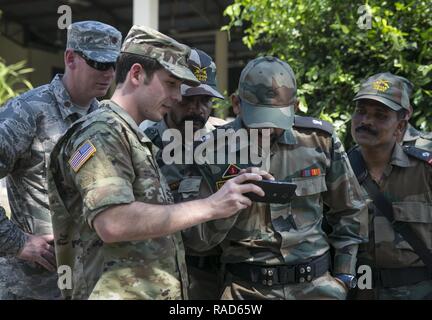 U.S. Army Lt. Canyon Yeamans from the 83rd Civil Affairs Battalion, shows photos to leaders of the Indian Army at Ban Non Lueam School in Korat Province Jan. 27, 2017. Yeamans, a Columbus, Ohio native, is a civil affairs team leader while supporting Cobra Gold 2017. The U.S. Air Force worked alongside the RTA, Indian Army and China’s People’s Liberation Army to begin building a multipurpose room for the Ban Non Lueam School, which will improve the quality of life of civilian residents in the area. Stock Photo