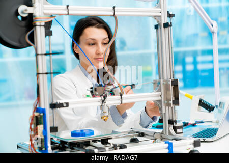female student or laboratory assistant in the automation laboratory is debugging the work of the 3d printer. 3d printer is a device for modeling objec Stock Photo