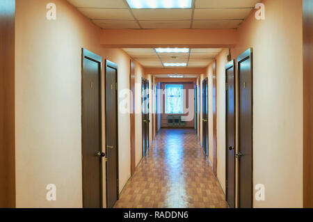 Perspective view of old school or office building hallway corridor, empty narrow, tall and long death end walkway with many doors room and windows. Stock Photo