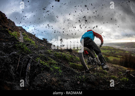 A mountain bike sends mud spraying into the air riding a trail on a rainy winter's day in South Wales. Stock Photo